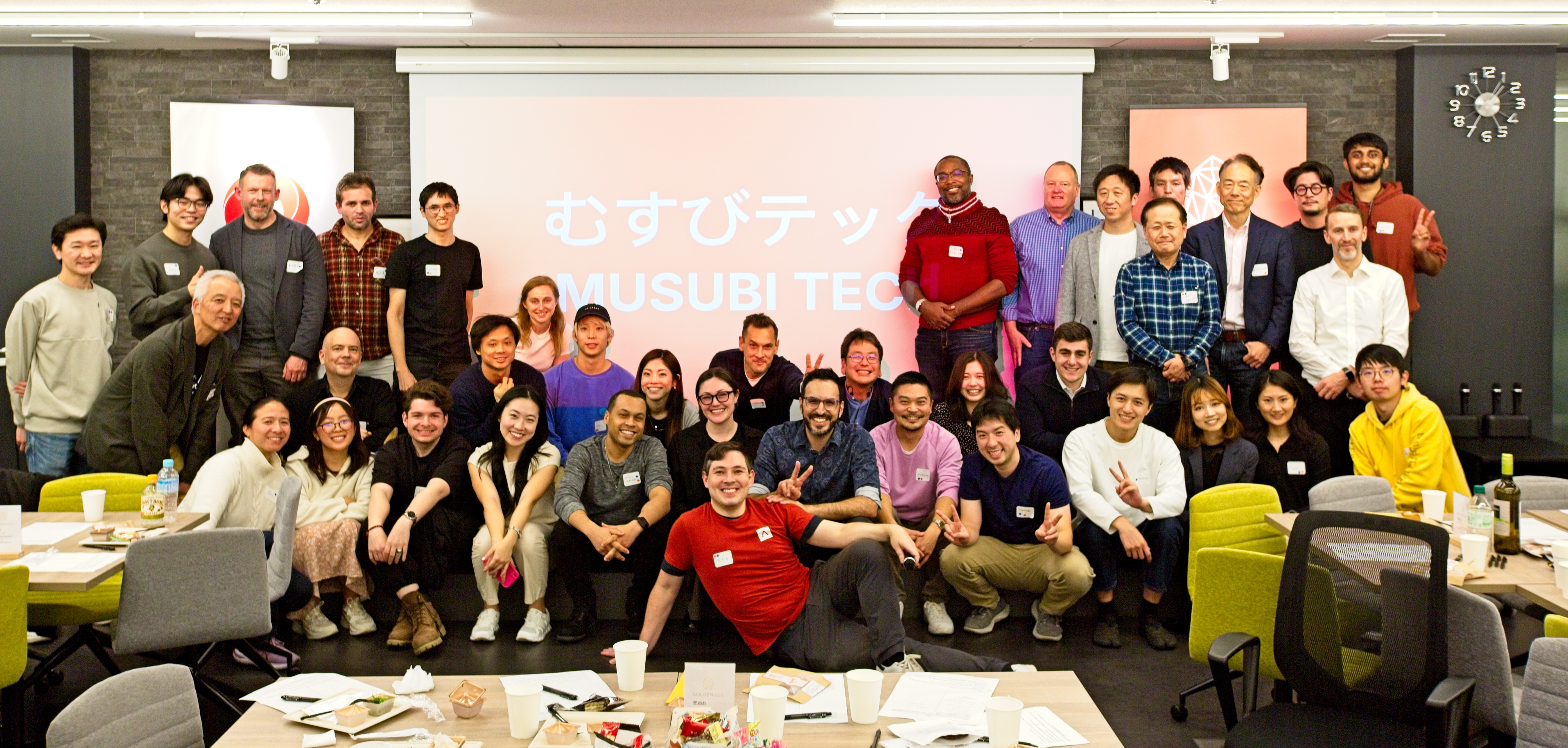 The Musubi Tech community gathered together under the projected logo