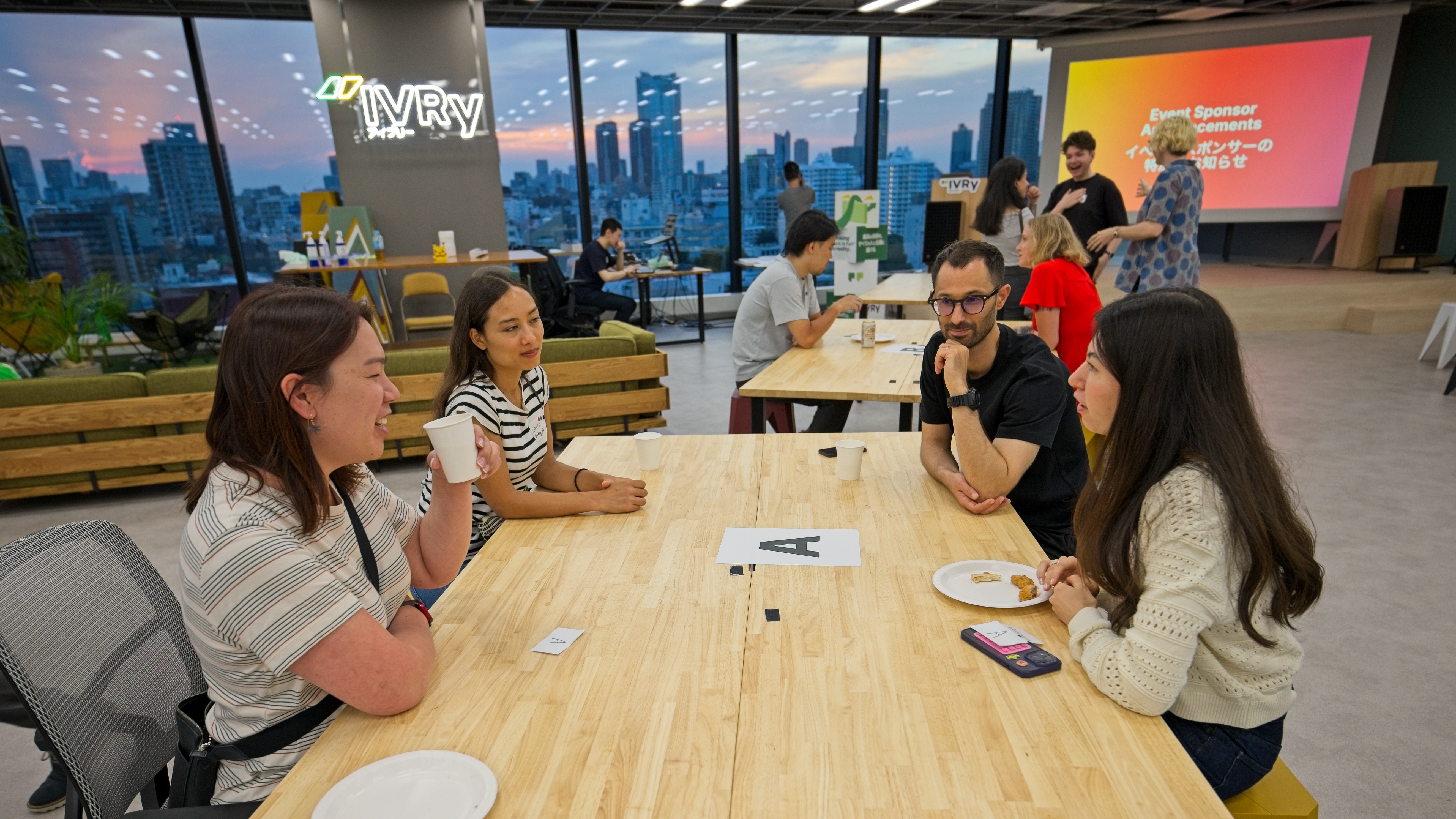 A small group in conversation at a table overlooking the Tokyo skyline